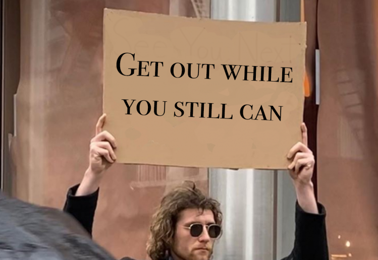 Guy with a sign saying "Get out while you still can"